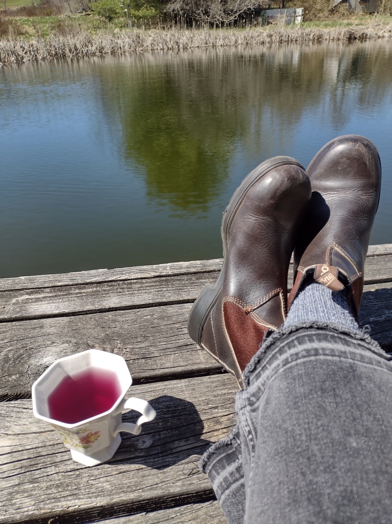photo of cup of tea and boots overlooking pond